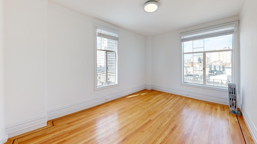 A room with wooden floors and two windows.